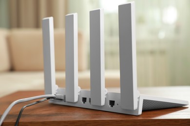 Photo of New modern Wi-Fi router on wooden table indoors, closeup