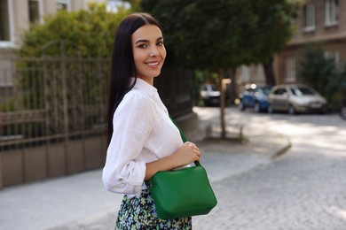 Beautiful young woman with stylish bag on city street