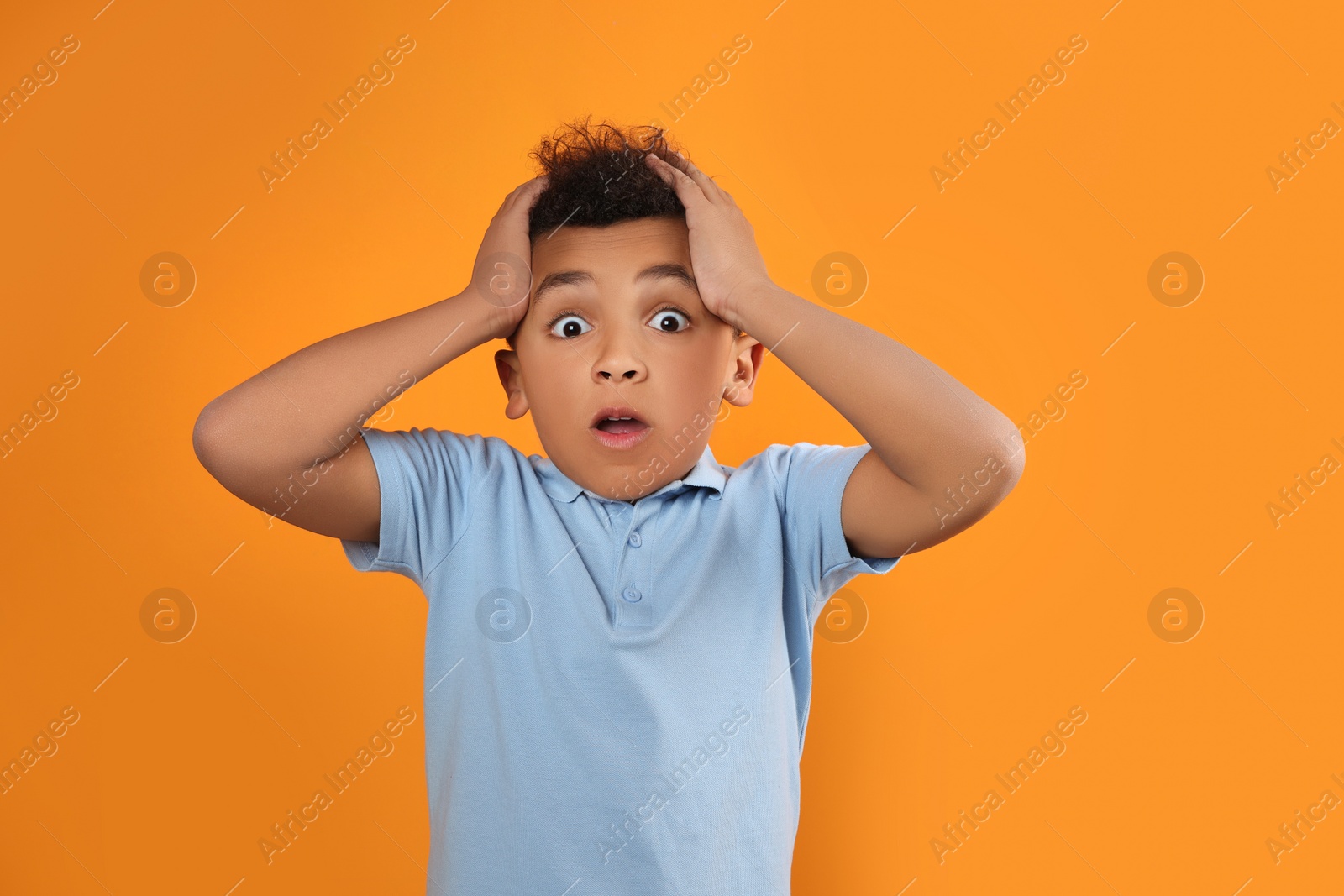 Photo of Portrait of emotional African-American boy on orange background