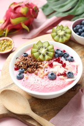 Photo of Tasty smoothie bowl with fresh kiwi fruit, berries and granola on pink table