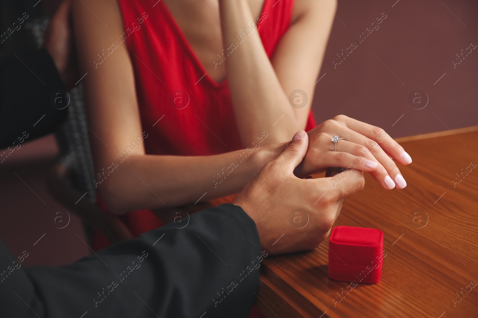 Photo of Man with engagement ring making proposal to his girlfriend at table, closeup