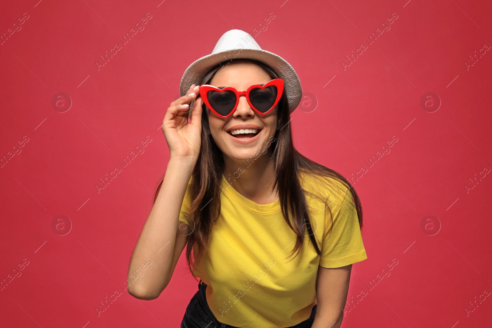 Photo of Portrait of beautiful young woman with heart shaped sunglasses on color background