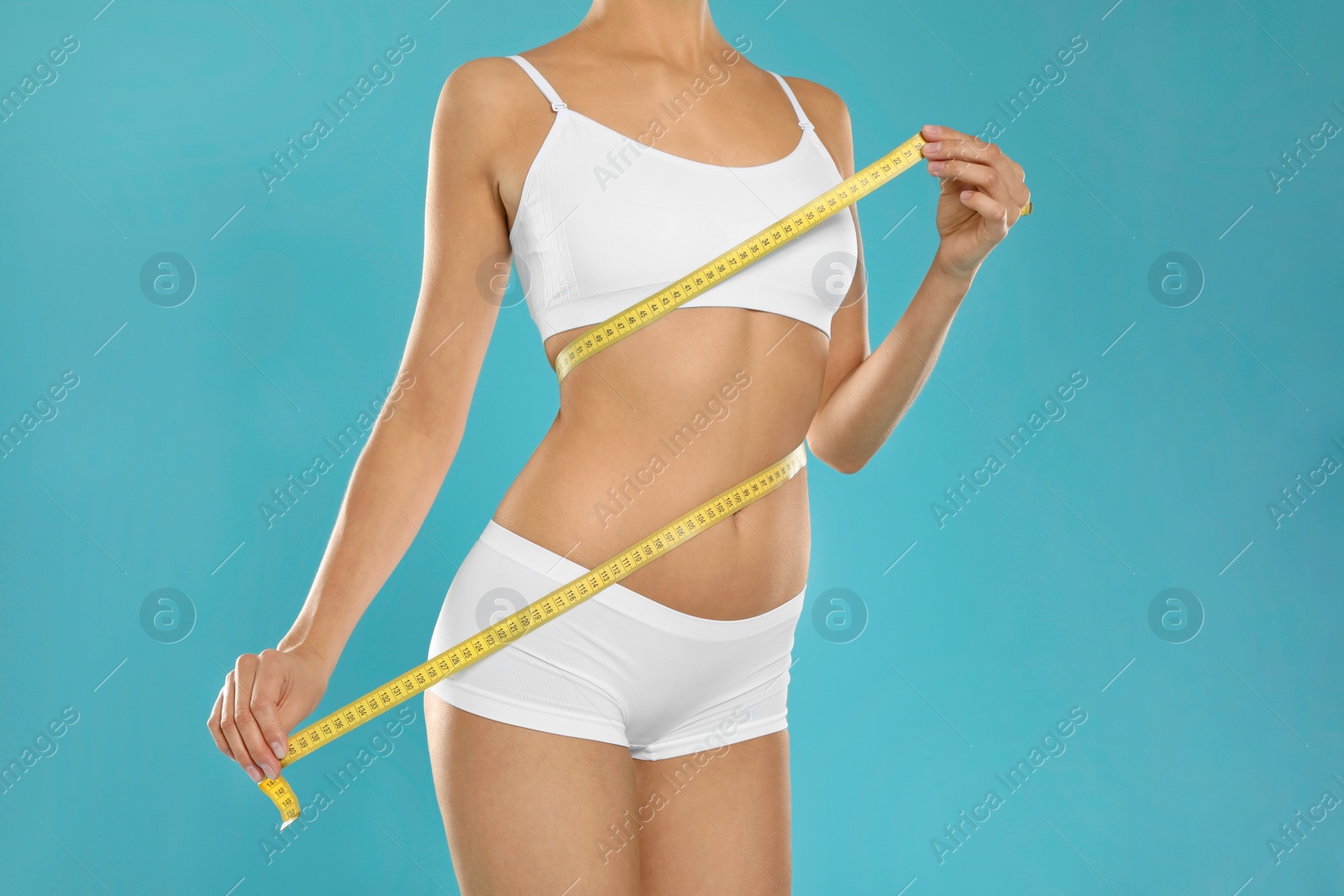 Photo of Slim young woman with smooth gentle skin in underwear measuring body on color background