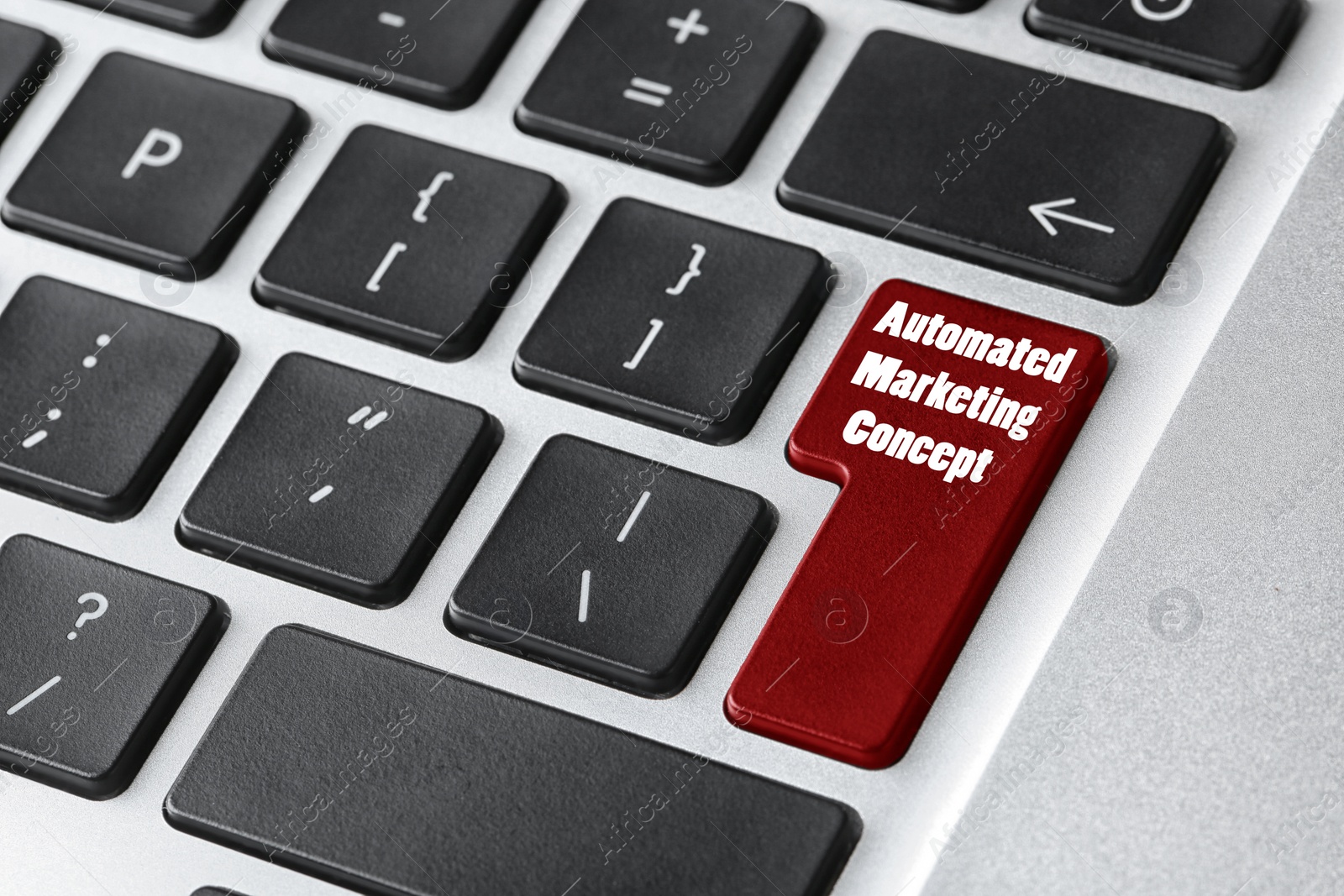 Image of Modern laptop keyboard with text AUTOMATED MARKETING CONCEPT on button, closeup