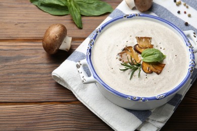 Delicious homemade mushroom soup in ceramic pot and fresh ingredients on wooden table. Space for text