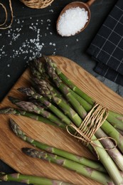 Photo of Fresh raw asparagus on black table, flat lay