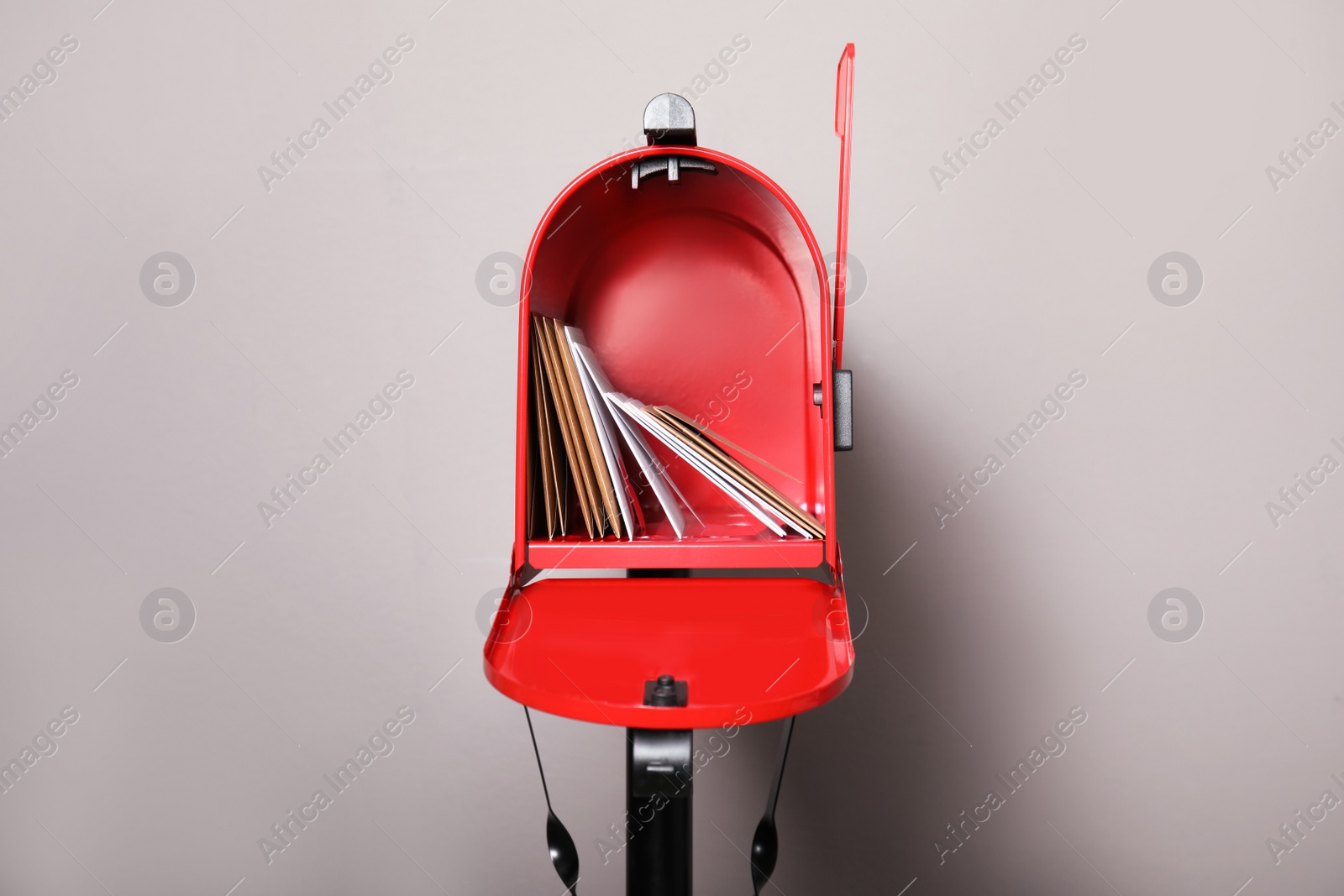 Photo of Open red letter box with envelopes against grey background