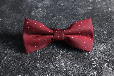 Photo of Stylish red bow tie on black textured background