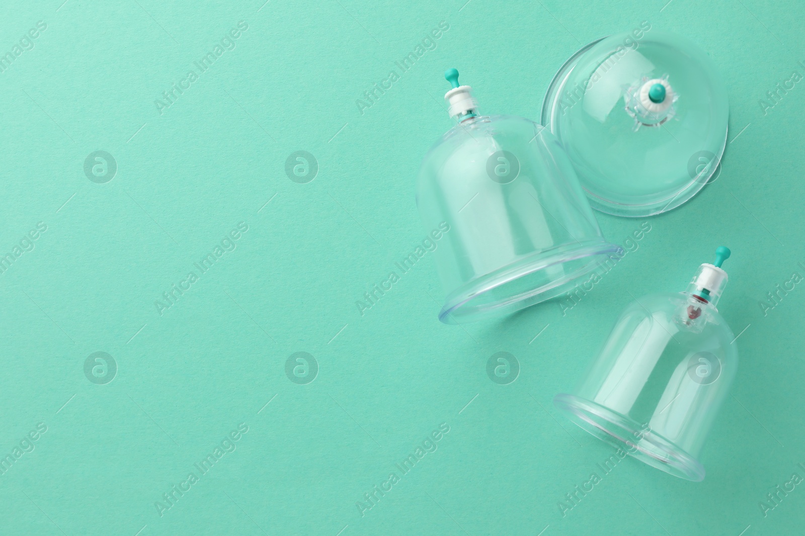 Photo of Plastic cups on turquoise background, flat lay with space for text. Cupping therapy
