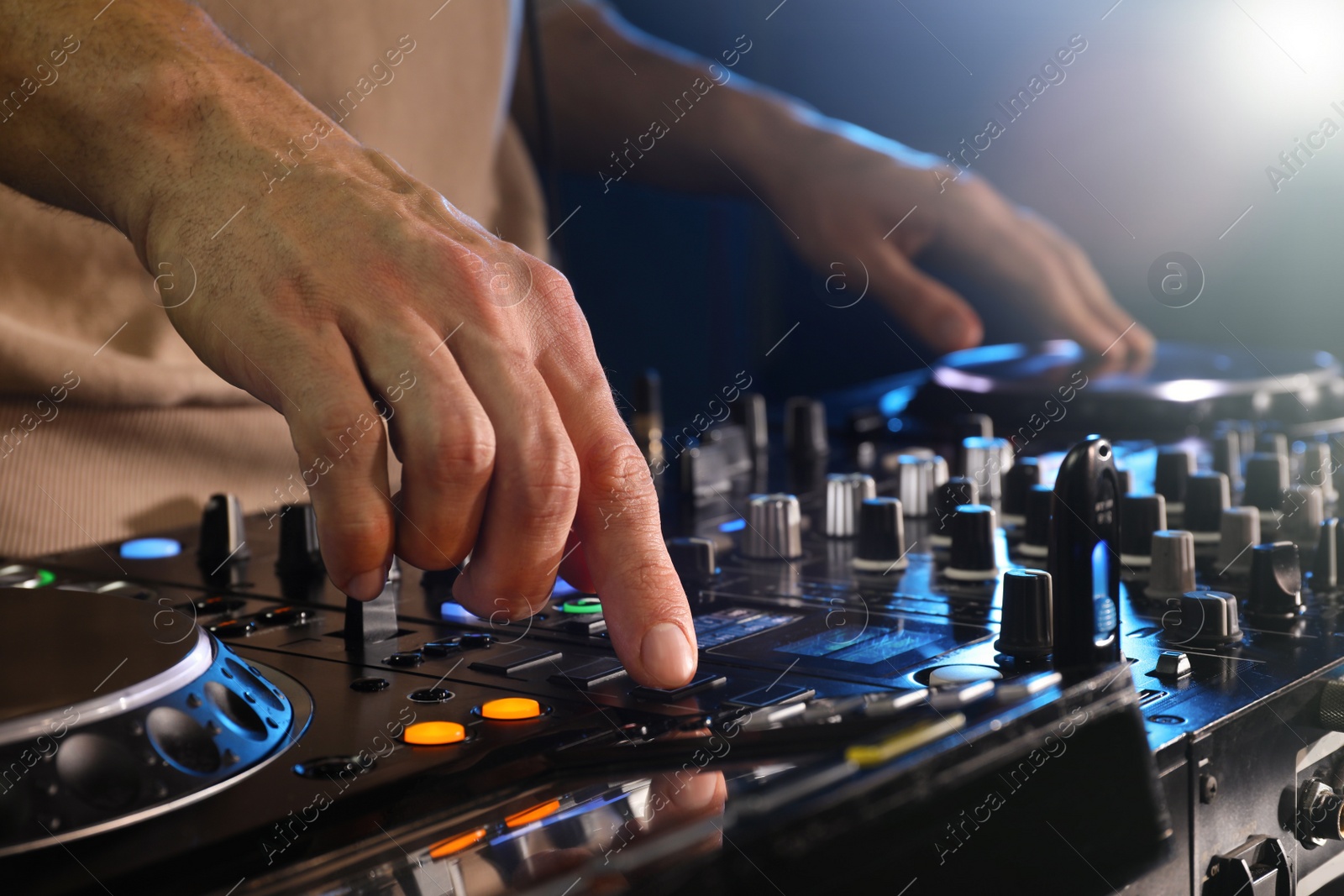 Photo of DJ creating music on modern console mixer in night club, closeup