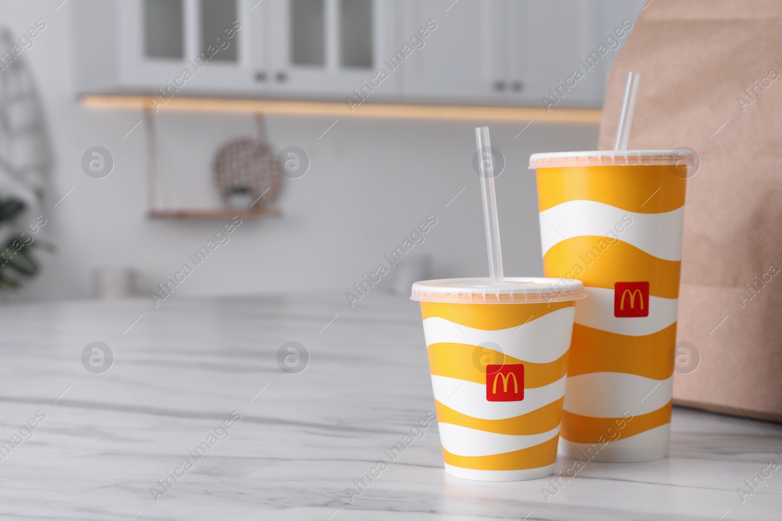 Photo of MYKOLAIV, UKRAINE - AUGUST 12, 2021: Cold McDonald's drinks and packed food on marble in kitchen. Space for text