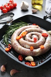 Photo of Pan with raw homemade sausage, chili pepper, garlic and rosemary on grey table, closeup