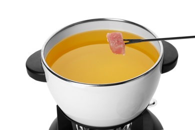 Photo of Dipping raw meat into fondue pot with oil on white background