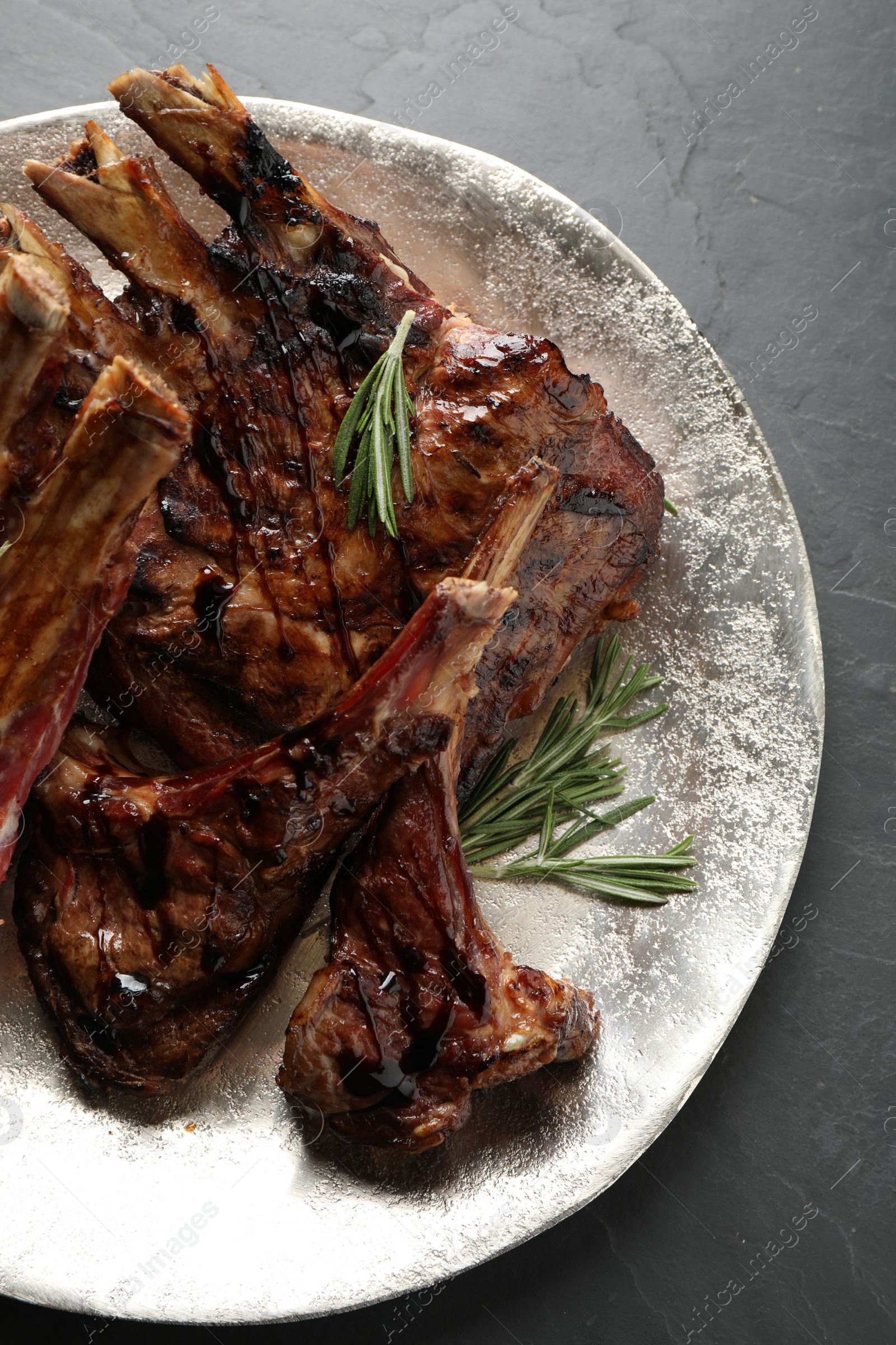 Photo of Delicious grilled ribs served on black table, top view