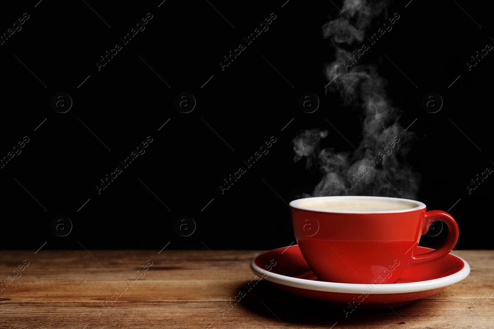 Image of Red cup with hot steaming coffee on wooden table against black background, space for text