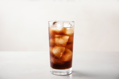 Photo of Glass of refreshing cola with ice on white table