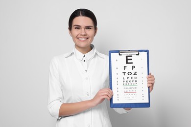Photo of Ophthalmologist with vision test chart on light background
