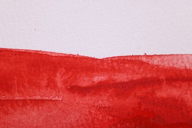 Abstract red watercolor painting on white paper, top view