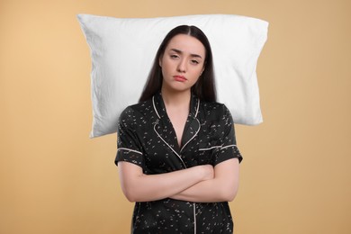 Photo of Tired young woman with pillow on beige background. Insomnia problem