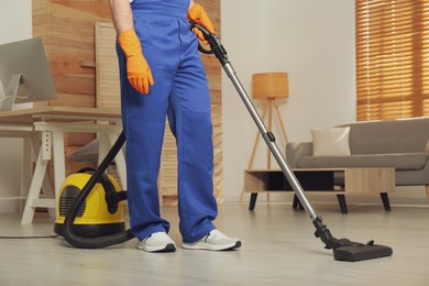 Photo of Janitor in uniform vacuuming floor indoors, closeup