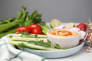 Plate with delicious hummus and fresh vegetables on table