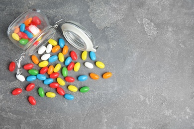 Overturned jar with jelly beans on stone background, top view. Space for text