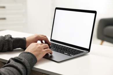 E-learning. Young man using laptop at white table indoors, closeup