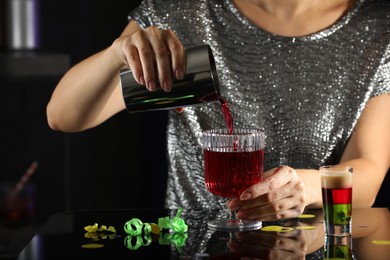 Photo of Woman pouring cocktail into glass indoors, closeup