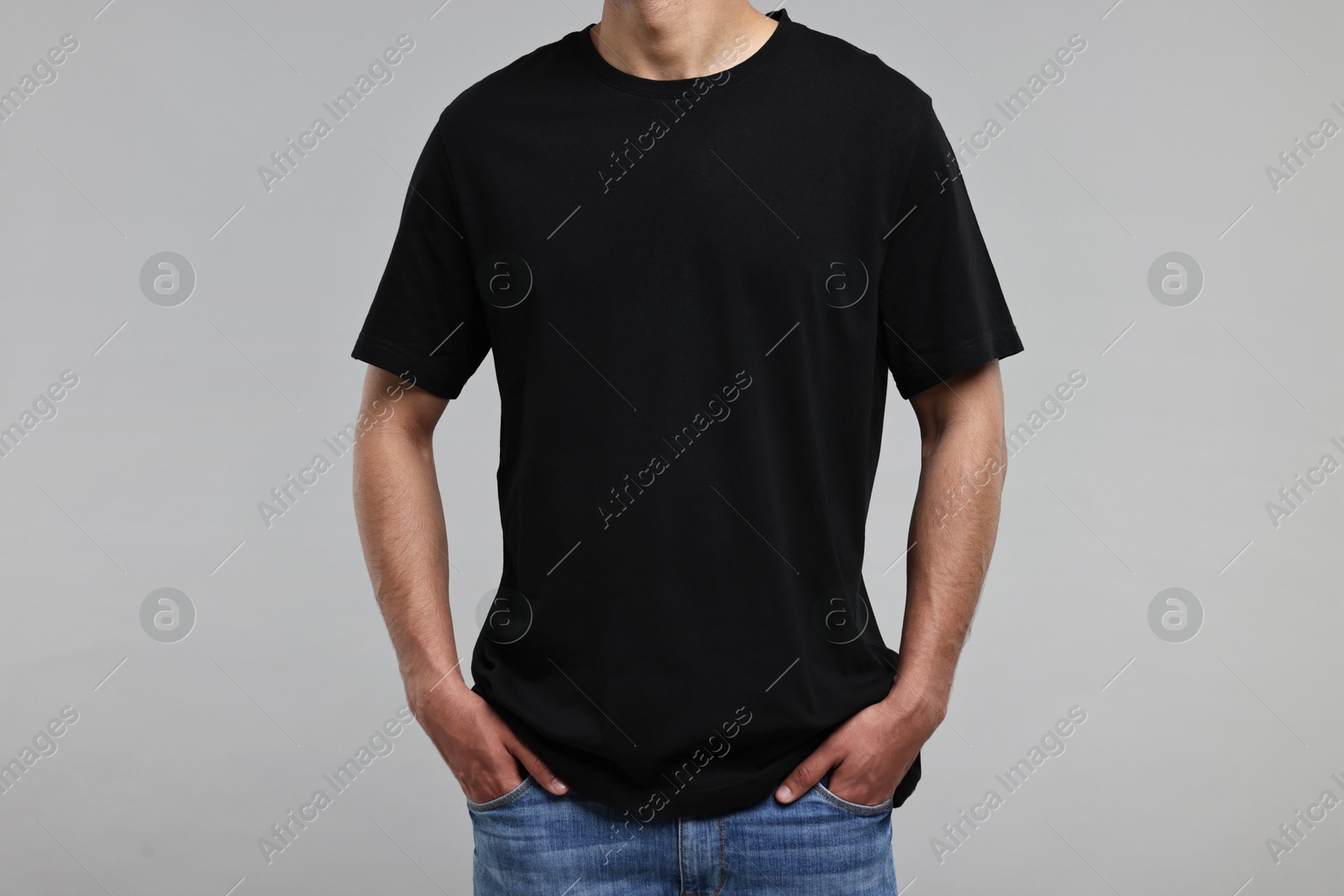 Photo of Man in black t-shirt on grey background, closeup