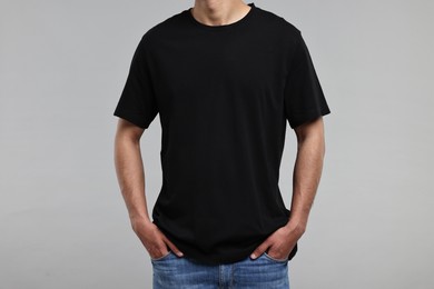 Photo of Man in black t-shirt on grey background, closeup