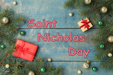 Image of Saint Nicholas Day. Flat lay composition with fir branches and gifts on blue wooden background