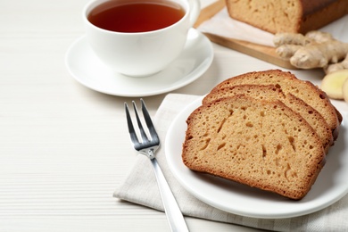 Slices of delicious gingerbread cake served with tea on white wooden table