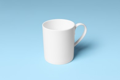 Photo of White ceramic mug on light blue background