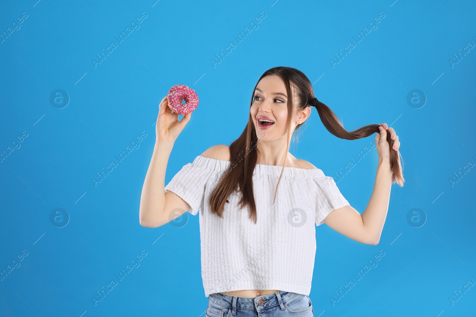 Photo of Beautiful young woman with donut on light blue background