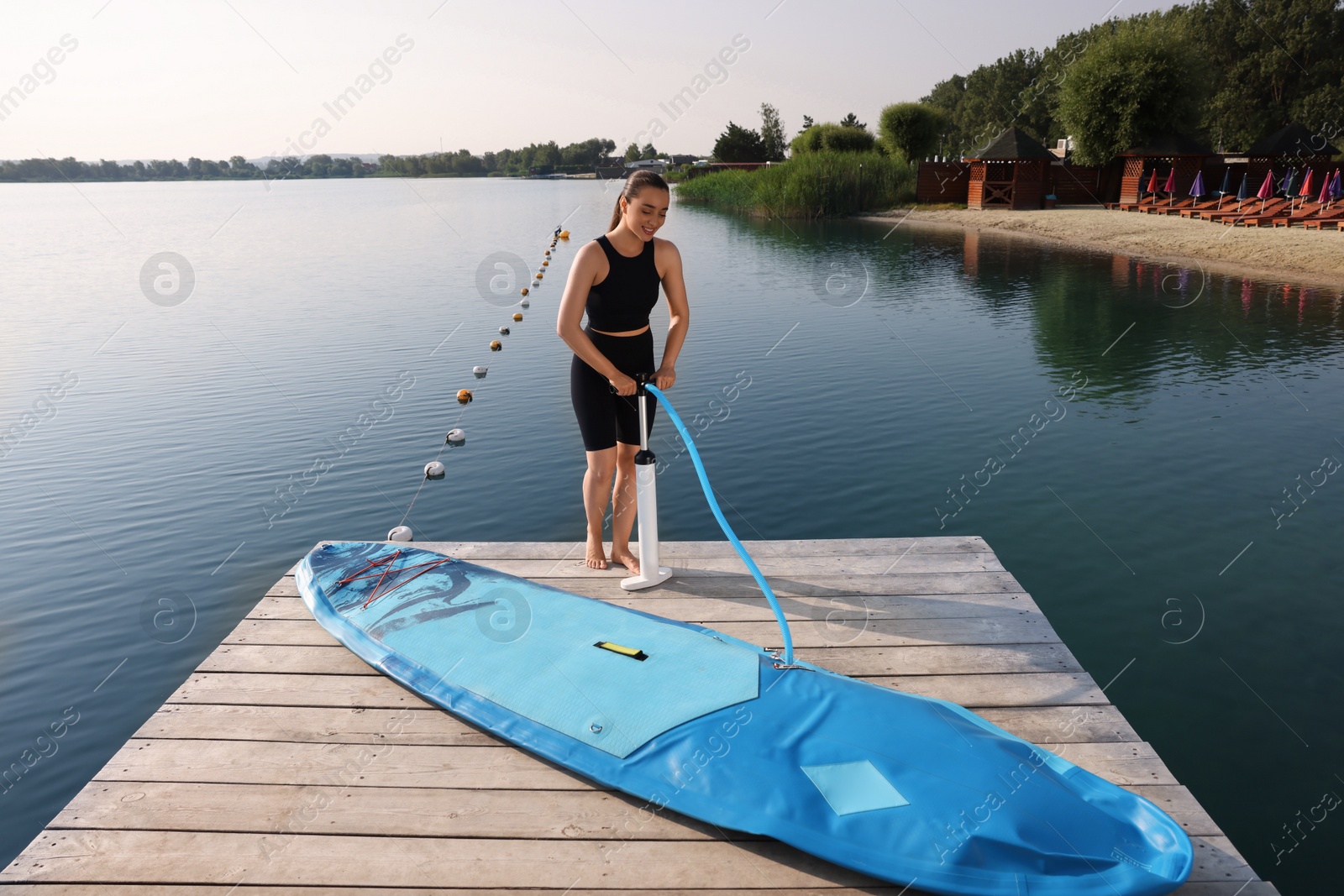 Photo of Woman pumping up SUP board on pier