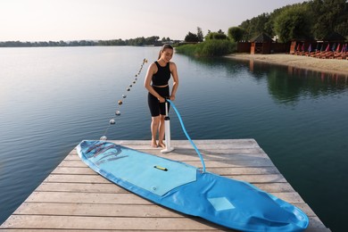 Woman pumping up SUP board on pier