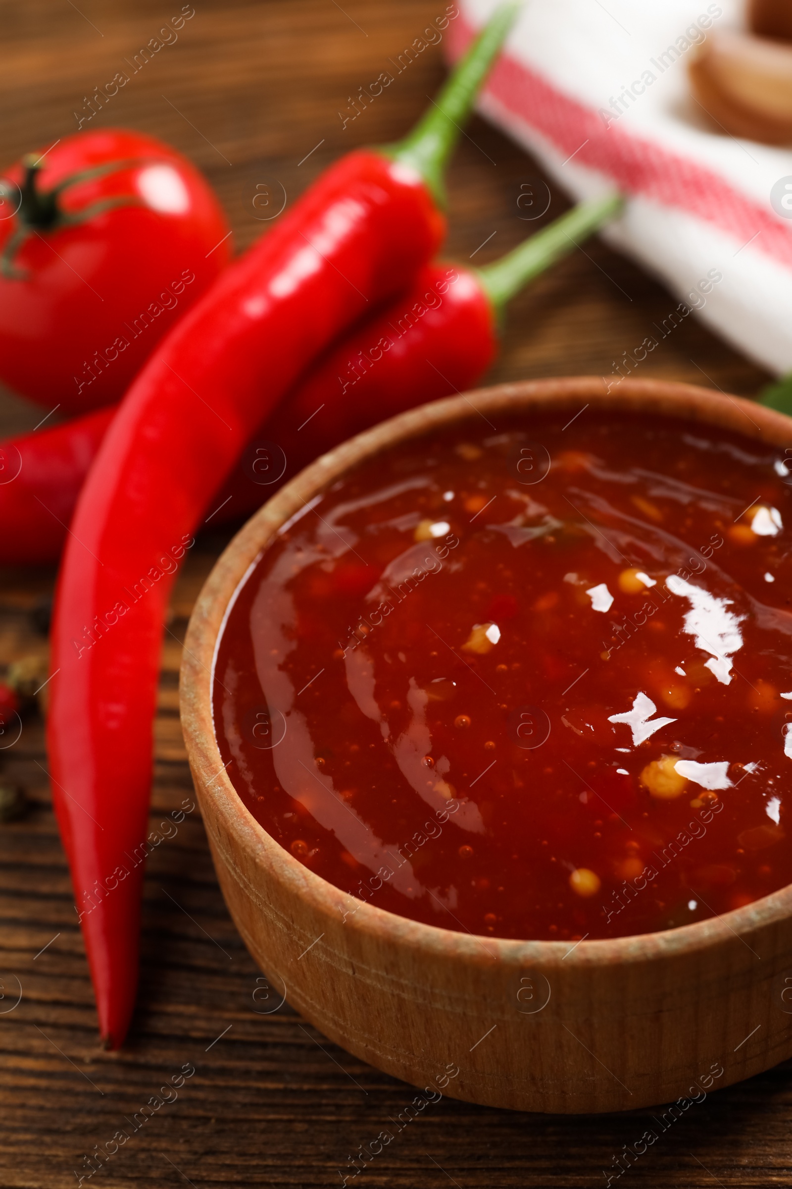 Photo of Spicy chili sauce in bowl on wooden table