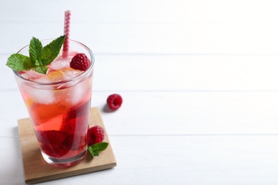 Photo of Delicious raspberry lemonade made with soda water and ingredients on white wooden table. Space for text