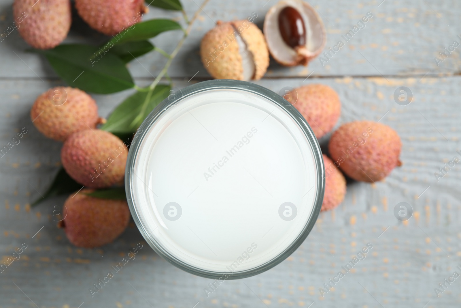 Photo of Fresh lychee juice and fruits on grey wooden table, flat lay