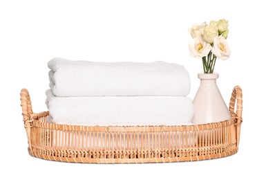 Photo of Wicker tray with folded soft terry towels and flowers on white background