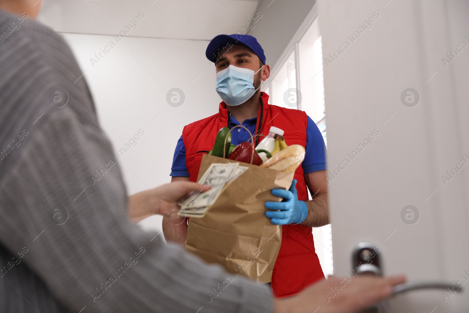 Photo of Young woman giving tips to courier indoors, closeup