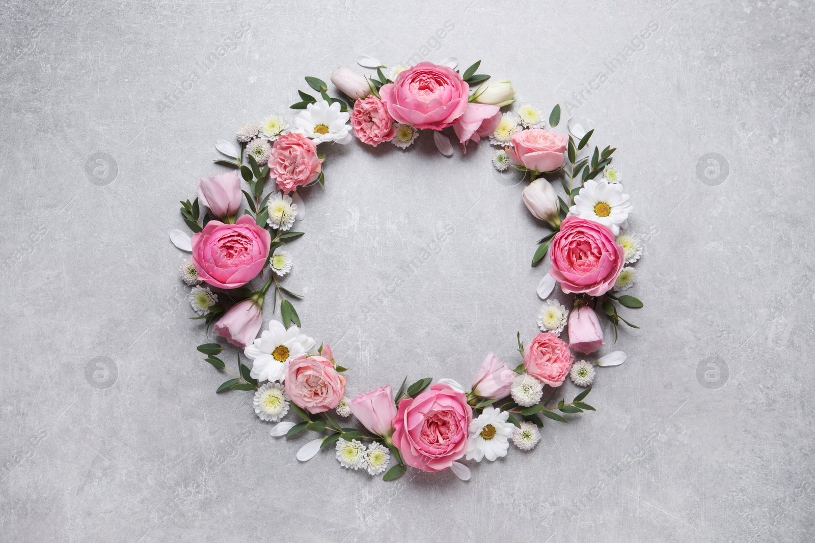 Photo of Wreath made of beautiful flowers and green leaves on light grey background, flat lay. Space for text