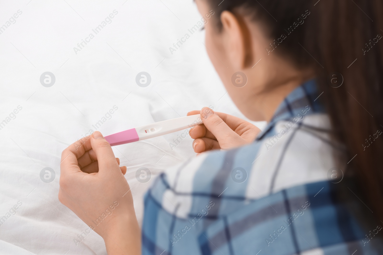 Photo of Young woman with pregnancy test on bed, closeup. Gynecology and childbirth