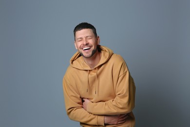 Handsome man laughing on grey background. Funny joke