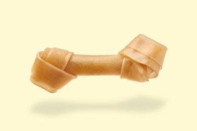 Image of Bone dog treat in air on beige background