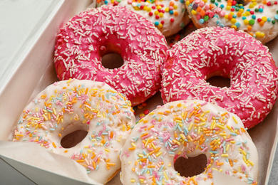 Photo of Sweet delicious glazed donuts in box, closeup