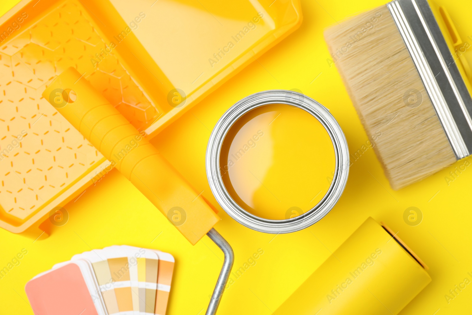 Photo of Flat lay composition with can of paint, brush and renovation tools on yellow background