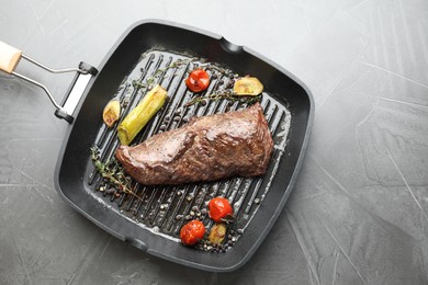 Photo of Delicious grilled beef meat and vegetables in pan on grey table, top view