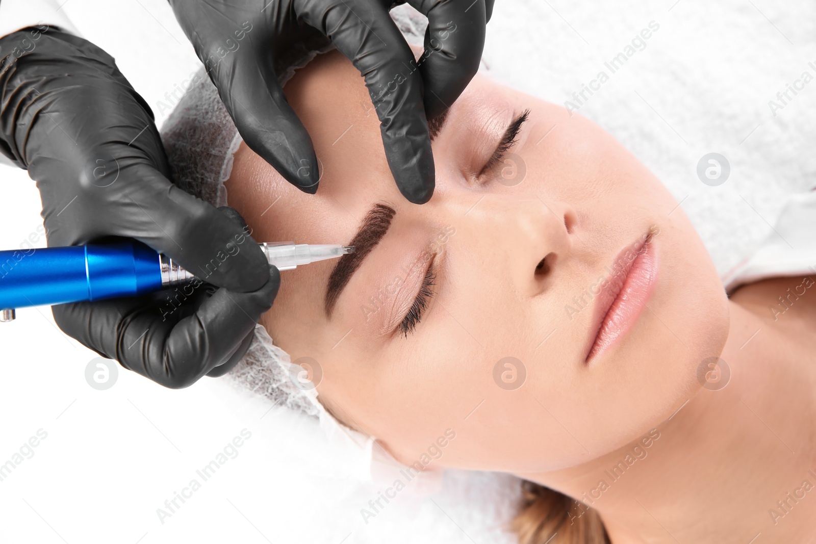 Photo of Young woman undergoing eyebrow correction procedure in salon