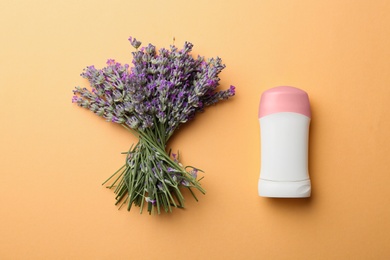 Photo of Female deodorant and lavender flowers on apricot background, flat lay